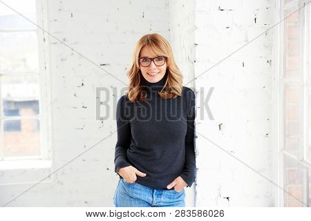 Portrait Of Attractive Woman Wearing Roll Neck Sweater And Jeans While Looking At Camera And Smiling
