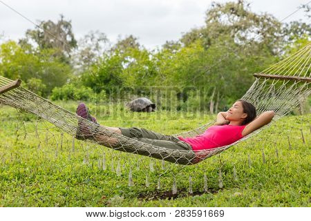 Ecotourism Travel adventure on Galapagos Islands. Tourist woman relaxing in hammock by Giant Tortoise Santa Cruz Island in Galapagos Islands.