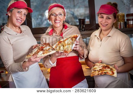 Smiling Young Stuff Aprons Selling Pizza In Fast Food Restaurant. Tasty Italian Food