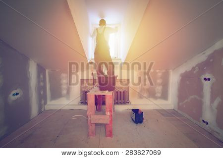 Worker Is Installing Pvc Window From Wooden Platform In Small Romm Of  Apartment That Is Under Const
