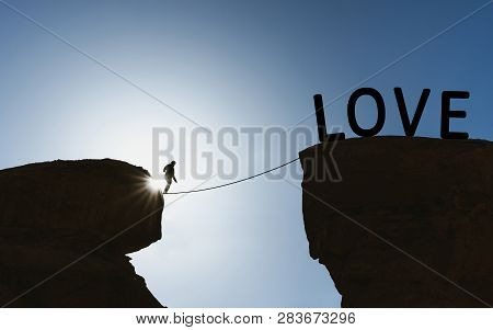 Silhouette A Man Walking On Rope Over Precipice To Love. Loves Concept