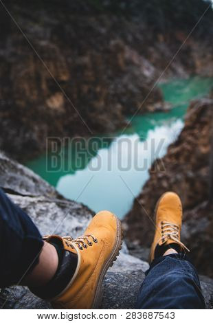 Feet Of Nature Explorer Sitting Over Mountain River Canyon