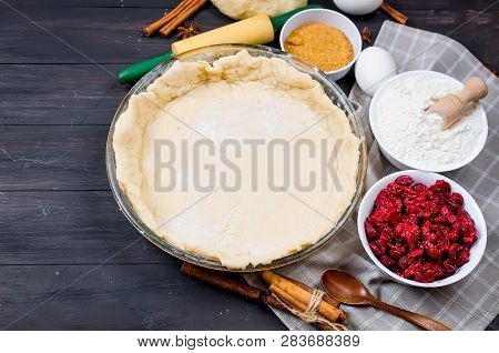 Pie Base In A Glass Round Form And Ingredients For Making Cake  - Flour, Egg, Cherry, Brown Sugar, C
