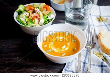 Serving For Lunch, Homemade Pumpkin Soup In White  Bowl And Fresh Light Green Salad Of Vegetables An