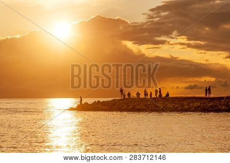 Tourists And Fishermen Watching Amazing Sunset From The Pier Of Mandre Village On Pag Island, Croati