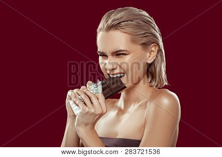 Blonde-haired Model With Bob Cut Needing Much Effort To Bite Chocolate