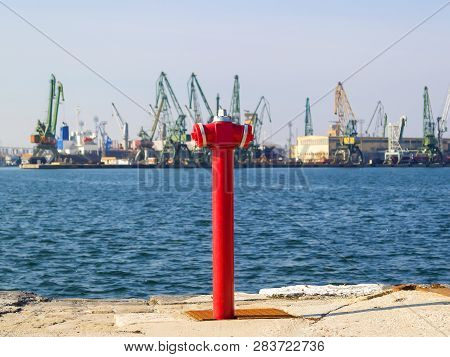 Red Fire Hydrant At The Edge Of The Pier. The  Seaport On A Sunny Day.  Fire Safety And Fire Fightin