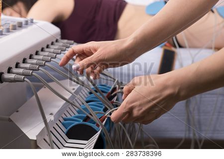 Young Woman Taking Myostimulation At The Nutritionists Office, Close-up Of The Equipment And Doctors