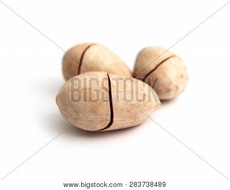 Three Unpeeled Pecan Nuts In Shell, With Cracks, Isolated On White Background.