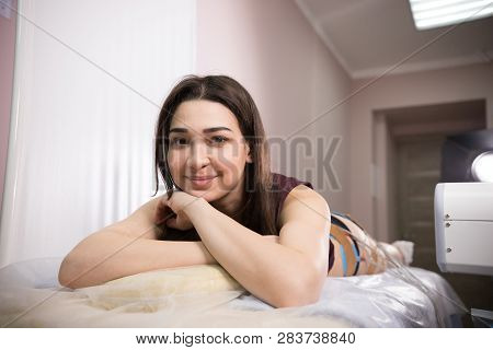 Cosmetology Beauty Clinic. Young Woman With Dark Hair Taking Myostimulation, Smiling And Looking At 