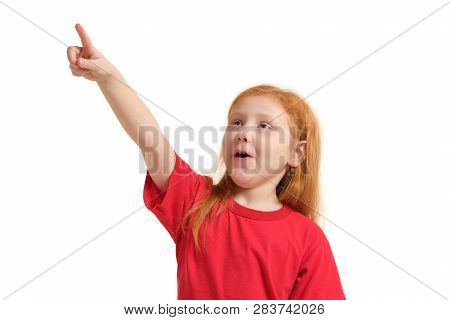 Education, School And Imaginary Screen Concept - Cute Little Girl Pointing In The Air Or Imaginary S