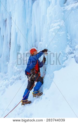 Ice Climber Preraring Running Belay, Screwing Ice Screw Into Glacier Surface