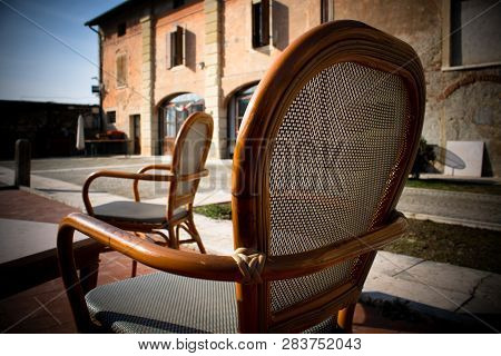 Two Cozy Chairs Standing In The Yard Near The Old Building