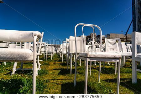 An installation of empty white chairs constitutes an unofficial temporary memorial for 185 people wh