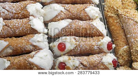 Background Of Stuffed Pastries With Red Cherry In Pastry Called Cannoli Siciliani In Italian Languag