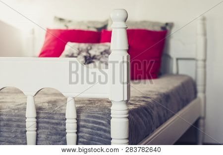 White Wooden Carved Bed With Gray Bedspread And Red Pillows