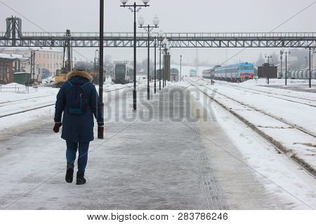 Person Walking On Empty Railway Platform, Frozen Platform In The Bitter Cold In Winter. Asphalt In T