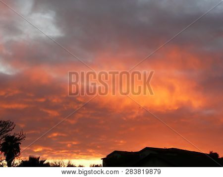 Dramatic Rich Orange Sunset With Silhouette Of Palm And Rooftop