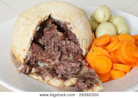 Et fad med en steak og nyre oksetalg budding, kogte nye kartofler og snittede gulerødder, en filippinsk