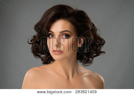 Beautiful Brunette With Volumed Hair, Stylish Make Up On Gray Background. Pretty Lady With Plump Lip