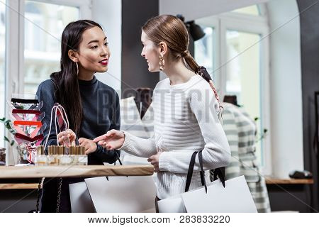 Brunette Beautiful Asian Woman In A Navy Polo Neck And Her Friend Looking Interested