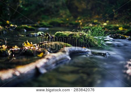 Long Exposure Of A River Creek With A Small Waterfall. Sunset And Strong Detail Bokeh View. Blue Cal