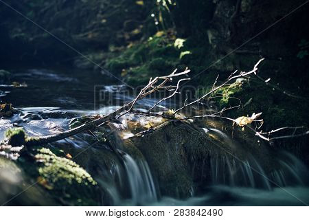 Long Exposure Of A River Creek With A Small Waterfall. Sunset And Strong Detail Bokeh View. Blue Cal