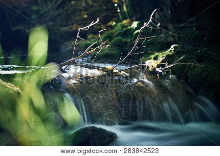 Long Exposure Of A River Creek With A Small Waterfall. Sunset And Strong Detail Bokeh View. Blue Cal