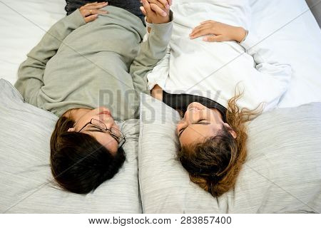 Senior Mom And Her Daughter Are Hugging, Smiling And Dringking A Warm Coffee In Some Morning.