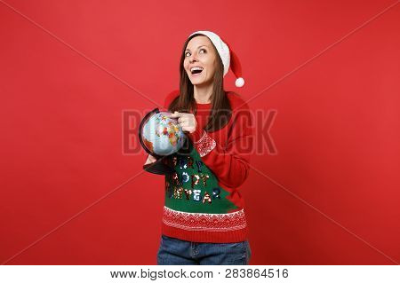 Dreamy Young Santa Girl In Christmas Hat Looking Up Keeping Finger On World Globe In Hands Isolated 