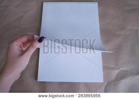 Female Hand Turns Over A White Sheet Album Which Lies Vertically On The Table