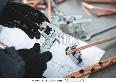 Engineer Is Holding In Hands A Brass Pipe And Is Measuring A Diameter By A Calipers. Pipework.