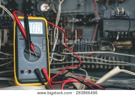 A Multimeter On A Electric Switchboard Background. Electric Work Concept Background.