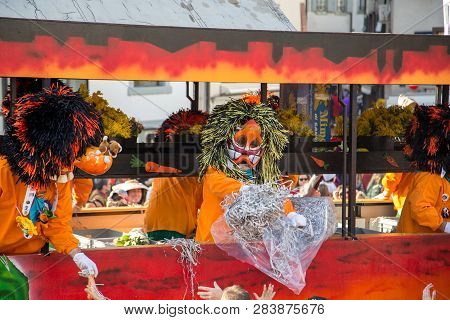 Basel, Switzerland - March 10, 2014: Dressed Up People Throwing Confetti At Spectators At The Tradti