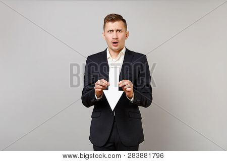 Shocked Worried Young Business Man In Classic Black Suit Shirt Holding Down Value Fall Arrow Isolate