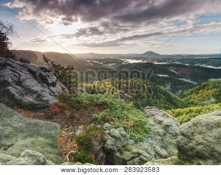Peak Of Sandstone Rock With View Into Colorful Mist In Morning Valley. Blue Eyllow Daybreak Sun Hidd