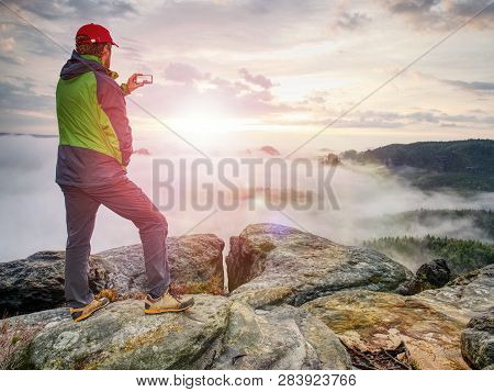 Hiker Takes Selfie Photo, Fall Nature Adventure. Man Sit On Stone On Mountain Sumit  Daybreak Horizo