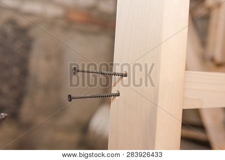 A Man Is Screwing A Screw Into A Wooden Table. Carpentry Workshop. Work With A Screwdriver.