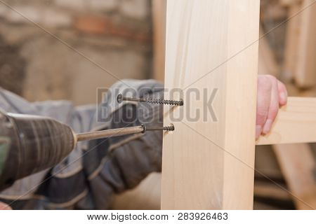 A Man Is Screwing A Screw Into A Wooden Table. Carpentry Workshop. Work With A Screwdriver.