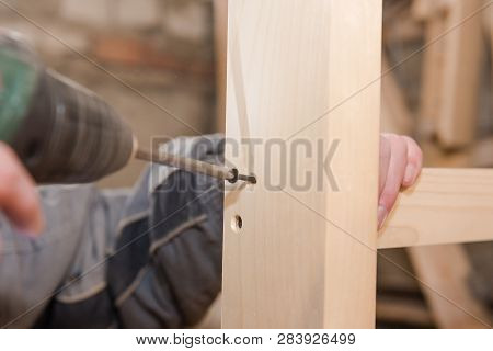 A Man Is Screwing A Screw Into A Wooden Table. Carpentry Workshop. Work With A Screwdriver.