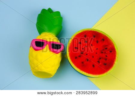 Top View Summer Vibrant Blue And Yellow  Background With Funny Pineapple Toy In Sunglasses And Squis