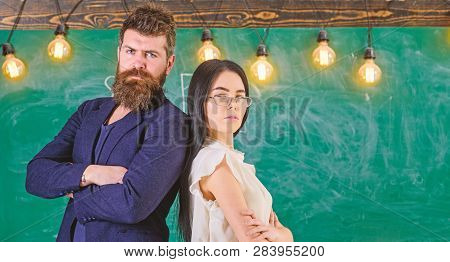 Man With Beard And Teacher In Eyeglasses Stand Back To Back, Chalkboard On Background. Teacher And S
