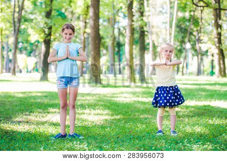 Little girls excersise together in sunshine park