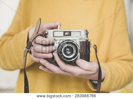 A Midsection Of A Girl Wearing Yellow Holding A Vintage, 35mm Camera Whilst Focussing The Lens With 