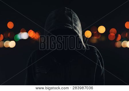 Hooligan With Hoodie And Obscured Face Walking The City Streets At Night, Looking Spooky And Threate