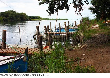 Rustic Craft Marina On A Swampy River Where Small Boats Moor In The Green Jungle In Tuscany