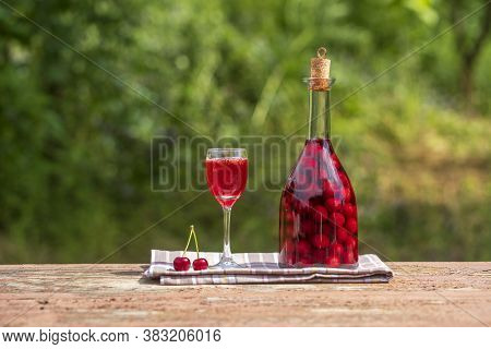 Homemade Tincture Of Red Cherry. Berry Alcoholic Drinks Concept. Red Wine Made In A Glass Bottle And