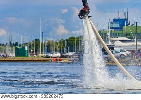 Man Having Fun On Flyboard. Flyboarding In A Sunny Summer Day At River In Harbor. Extrime Water Acti