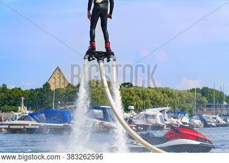 Man Having Fun On Flyboard. Flyboarding In A Sunny Summer Day At River In Harbor. Extrime Water Acti