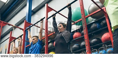 Group Of Athletes Grabbing The Bar Ready To Do Pull Ups In The Box